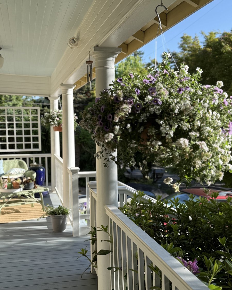 The front porch of Bobby's 115-year-old home, with hanging flower baskets and wind chimes