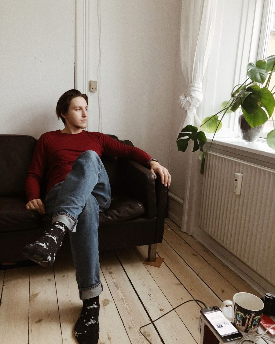 Her partner sitting on the couch, phone charging nearby, looking out the window