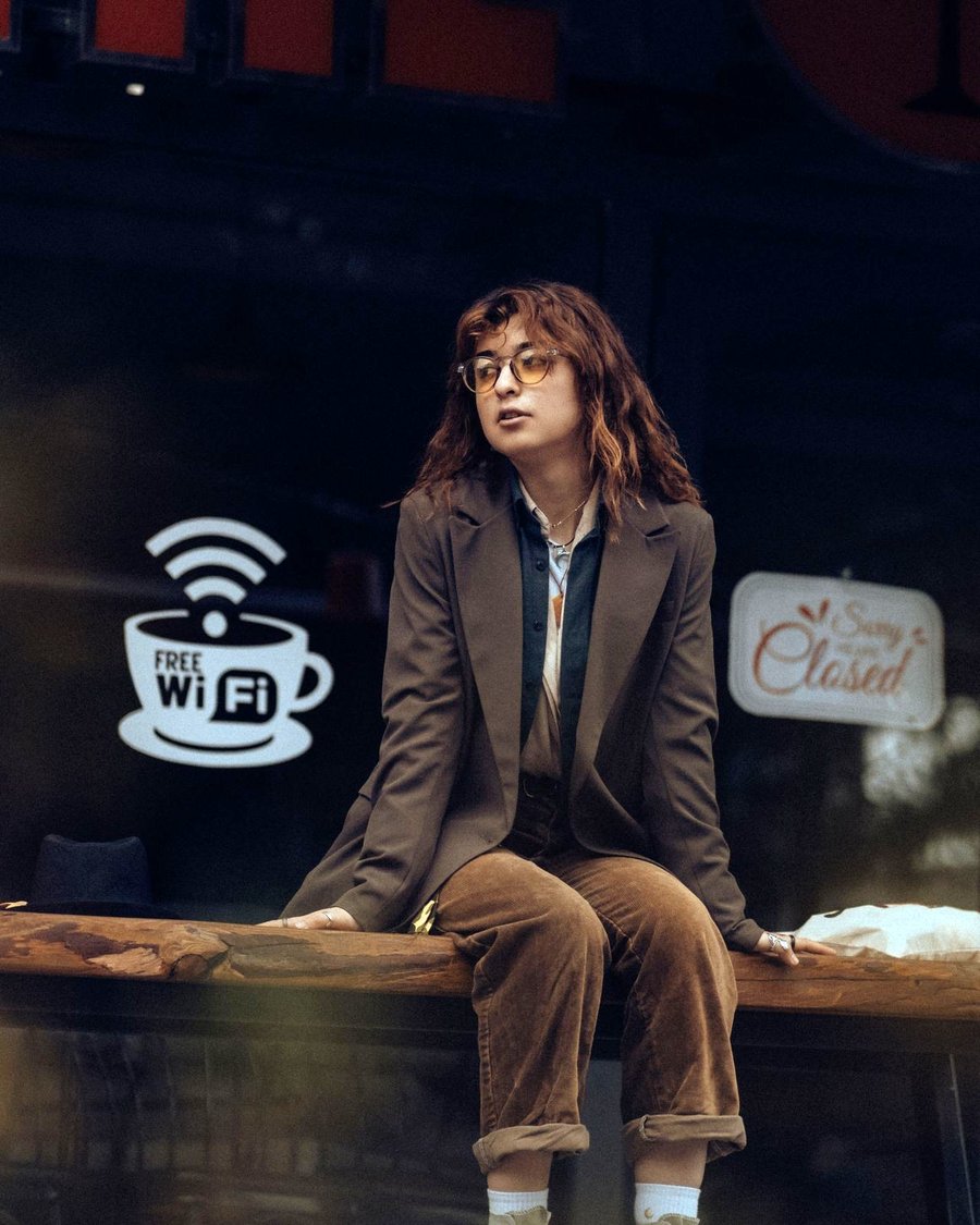 A person sitting beneath a Free Wi-Fi sign outside a closed cafe