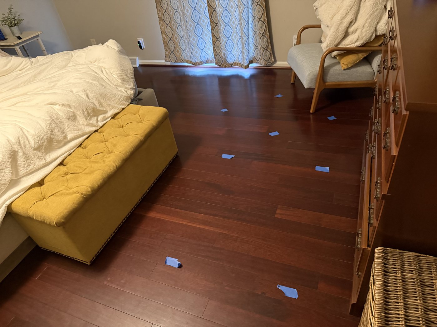 Measurement points marked with tape across a bedroom floor, leading toward the bed